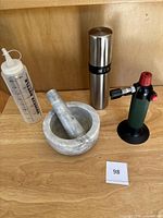 Full set including marble mortar and pestle, Misto oil sprayer, plastic squeeze bottle, and De Buyer blowtorch on wood surface.