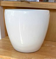 Side view of white ceramic planter showing smooth rounded shape and glossy finish.