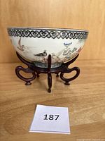 Front view of porcelain bowl on plastic stand showing floral and bird motifs