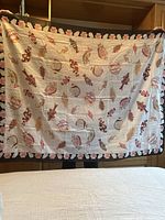 Full view of a light-colored cotton sarong with printed pattern held up for display, showing size and design.