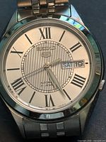 Close-up of watch dial showing Roman numerals and day-date window