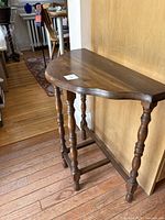 Side view showing half moon shape, turned legs, and stretcher base of the antique walnut side table.