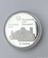 Front side of silver coin showing Montreal 1976 Olympiad design with city skyline, Olympic rings, and denomination '10 Dollars'.