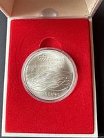 Silver coin in a red velvet-lined box with protective case.