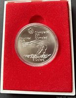 1975 Canada $5 sterling silver coin in red protective display case showing platform diver design from Montreal Olympics 1976 with inscriptions and denominations.