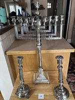 Overview: ornate menorah on counter with two matching candlesticks in front