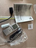 Sony UX512 IC recorder with headphones, USB cable, and manual laid out on table