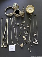 All items laid out on black background, showing necklaces, earring pairs, bracelet, brooch and ring box