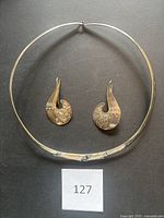 Full overview of matching sterling silver earrings and choker necklace laid flat against black background, showing overall design and relative size.