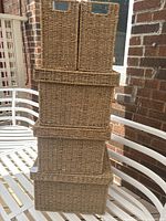 Five woven storage baskets stacked showing lids and open tops.