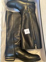 Pair of black pebbled leather boots in original box showing full side view with inside zipper