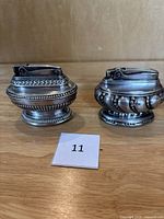 Two vintage silver plated Ronson table lighters displayed side by side showing overall shape and detailing.