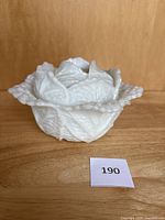 Front side view of white milk glass cabbage shaped bowl with lid, showing leaf texture and lid details