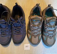 Photo showing the front view of two pairs of hiking shoes: purple Merrell and taupe Eddie Bauer.