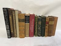Front view of the 13 older books standing upright showing titles and spines