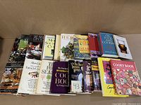 Front view of 19 cookbooks arranged side by side showing a variety of culinary topics and colorful covers.