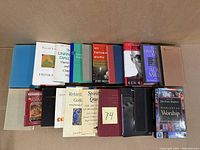 Photo showing full front view of all 20 books arranged side-by-side cover facing up on a table.