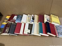 Photo showing 21 titles arranged in two rows, front and side cover views with varying designs and colors