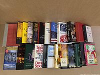 Photo shows the front covers and spines of 24 books in the lot, arranged upright side by side.
