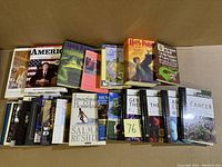 Top view photo of 24 books stacked in two rows showing titles including Harry Potter series, Grimm's Fairy Tales, Salman Rushdie, and various scientific and philosophical topics.