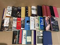 Photo of 32 hard and soft cover books stacked and arranged in two stacks, showing general titles and condition.