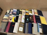 32 assorted books from various intellectual and cultural categories arranged in rows, showing diverse covers and bindings.