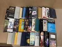 34 books in an open box viewed from above, showing variety of titles and bindings.