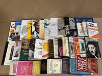 Two angled photos showing the front covers and spines of a mixed lot of 36 hardcover and paperback books arranged in two rows and two stacks, various subjects and authors.