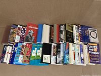 Photo showing a stack of assorted books including leadership, women issues, mystery, and classics, arranged standing and showing spines and covers.