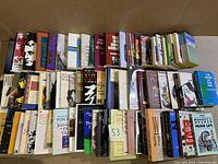 Wide angle photo showing 3 arranged rows of books on a flat surface with visible spines and covers, slight wear visible on edges