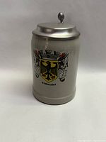 Front view of the beer stein showing the German eagle coat of arms and the metal lid.