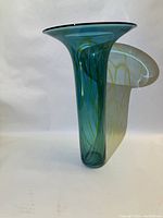 Front angle view of the tall blue-green glass vase with swirling green lines visible inside and a flared rim.