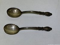 Two silver spoons with decorative Old Charleston handles shown together, good detail of overall size and style.