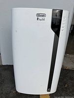 Front and side views of white DeLonghi Pinguino portable air conditioner with control buttons visible on right side panel.