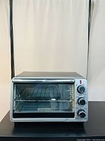 Full front view of BLACK+DECKER 6-slice convection toaster oven in silver and black with glass door and internal wire rack.
