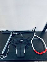 Jolly Jumper baby exerciser harness and accessories laid out on a dark surface showing the fabric seat, spring, chains, metal bar and rubber frame part.