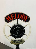 Close-up photo of the circular microphone head with Melody text and Microphone Since 1924 plaque