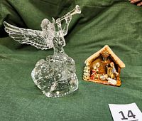 Clear acrylic angel tree topper and glazed ceramic nativity set displayed on green fabric background with measuring tape showing angel height around 9 inches.