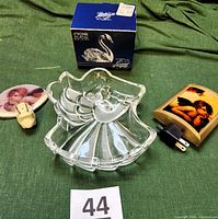 Photo of Masaka Germany angel-shaped crystal dish, Cristal dArques swan figurine in original box, and two cherub night lights with plugs visible, all displayed on green fabric.