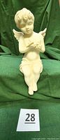 Front view of the 13-inch angel figurine seated with wings, holding doves, showing serene child-like face.