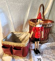 Photo showing both the large wicker basket with red cloth lining and the smaller square faux leather wrapped rattan basket with two front pockets, alongside the Pinocchio figurine.