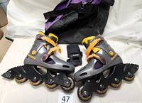 Pair of inline skates, wrist pads, and skate bag arranged on surface.