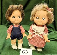 Front view of the vintage Campbell Soup Kids boy and girl dolls standing side by side, displaying their facial features, clothing, and shoes.