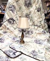 Comforter and two shams arranged with lamp centered on comforter, showing floral print and burgundy cording detail