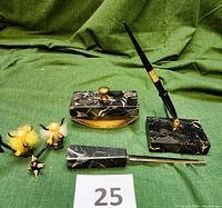 Full composition photo showing the black onyx marble desk set with pen holder, pen, letter opener, and rocking ink blotter with brass knob, alongside two Viking warrior figurines on a green backdrop.