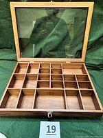 Open view of wooden shadow box showing 22 compartments inside for displaying items; glass top door open with gold-tone hinges and latch visible.