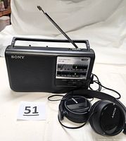 Front view of Sony ECF-38 portable radio with extended antenna and Sony headphones placed in front.