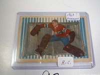 Front of card showing Cesare Maniago in goalie pose in Montreal Canadiens uniform, with striped background and plastic protective holder.