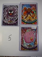 Front sides of 3 Pokemon cards showing Gastly, Hitmonchan, and Chansey with holographic backgrounds.