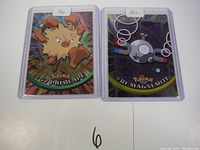 Two early 1st print Pokemon foil cards: Primeape (#57) and Magnemite (#81) in protective sleeves, showing holographic details.